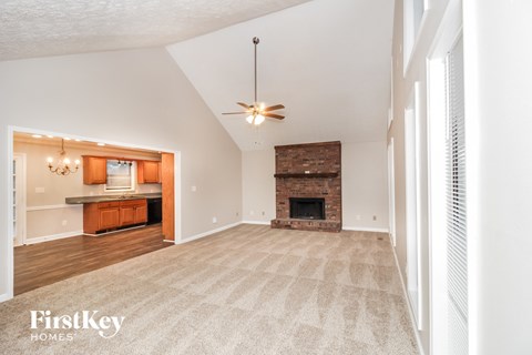 A spacious living room with a fireplace and a ceiling fan.