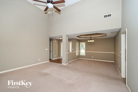 a living room with a ceiling fan and a large empty room