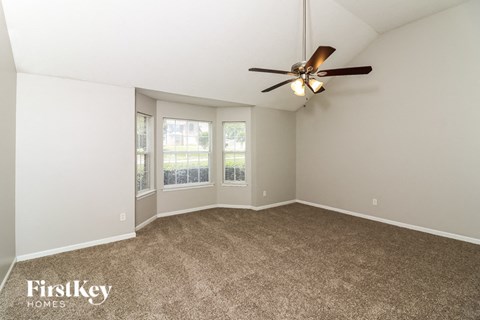 a living room with carpet and a ceiling fan