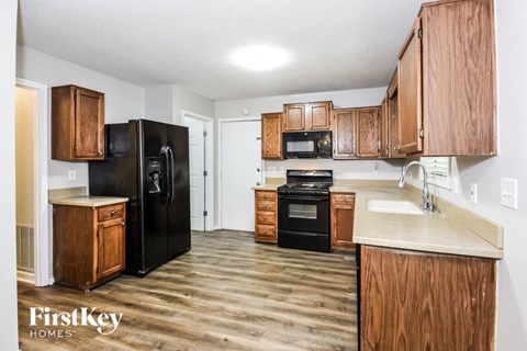 A kitchen with wooden cabinets and black appliances.