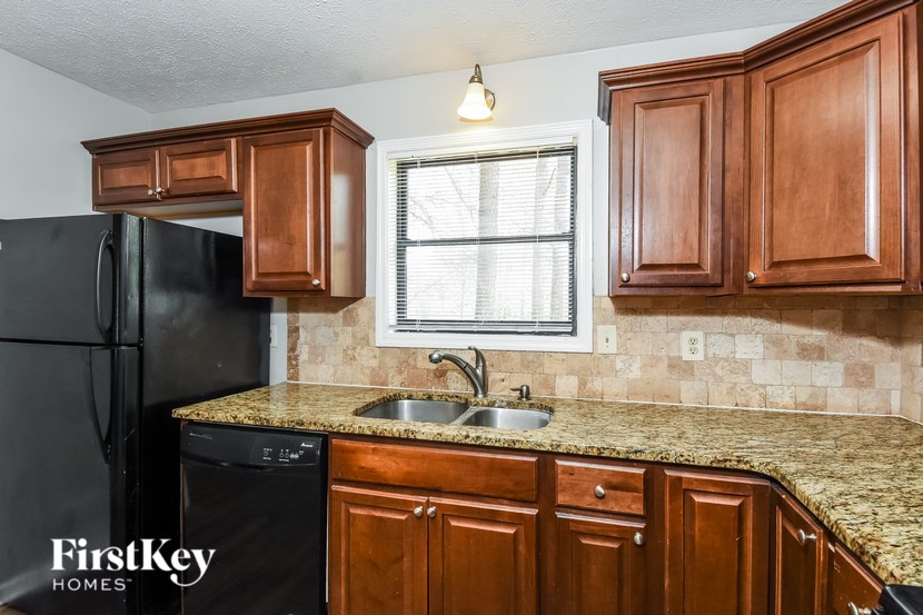A kitchen with brown cabinets and a black fridge.