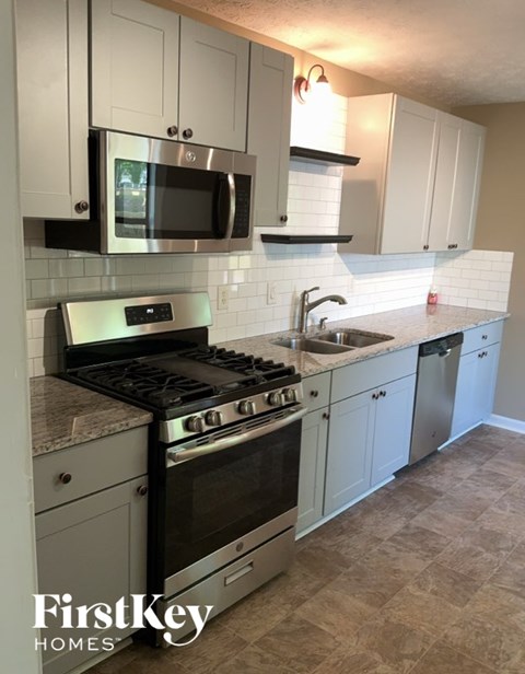 A kitchen with a black stove top oven and a black microwave above it.