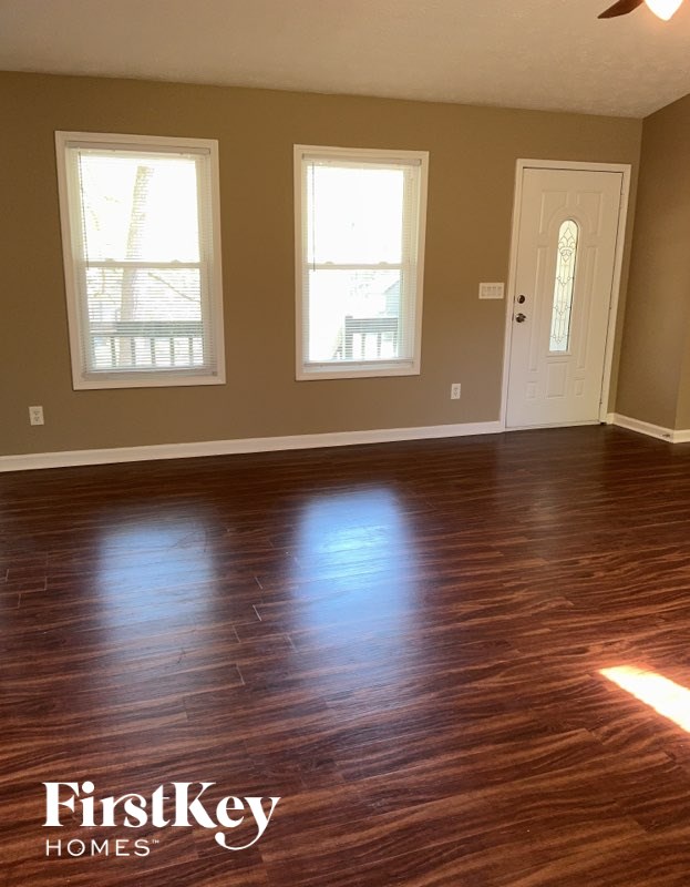A room with wooden floors and two windows.