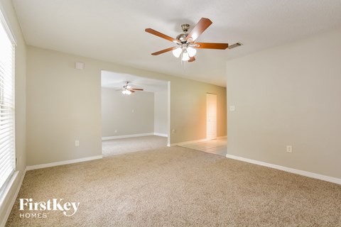 the spacious living room with ceiling fan and carpeting