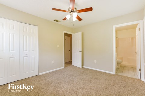 a bedroom with a ceiling fan and a door to a bathroom