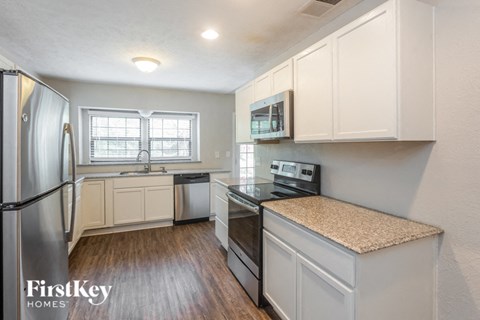 A kitchen with white cabinets and a stainless steel refrigerator.