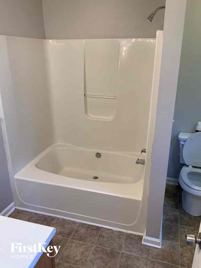 A white bathroom with a tub and toilet.