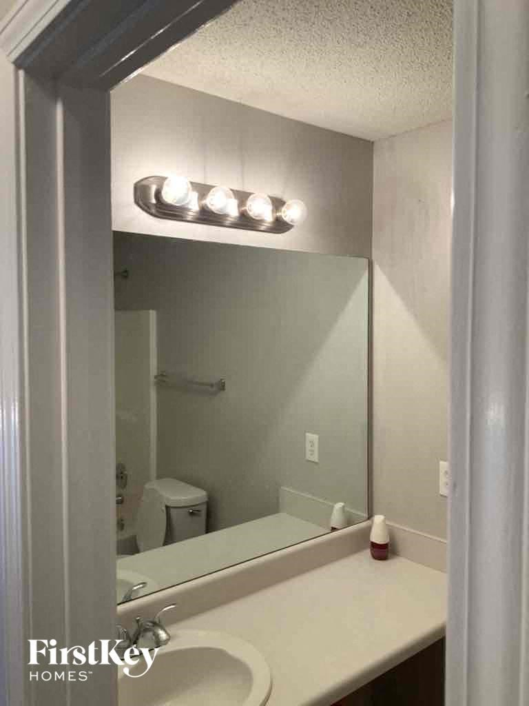 A bathroom with a mirror and lights above it.