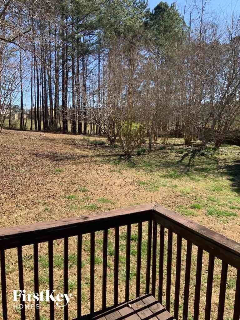 A wooden deck overlooks a grassy field with trees in the background.
