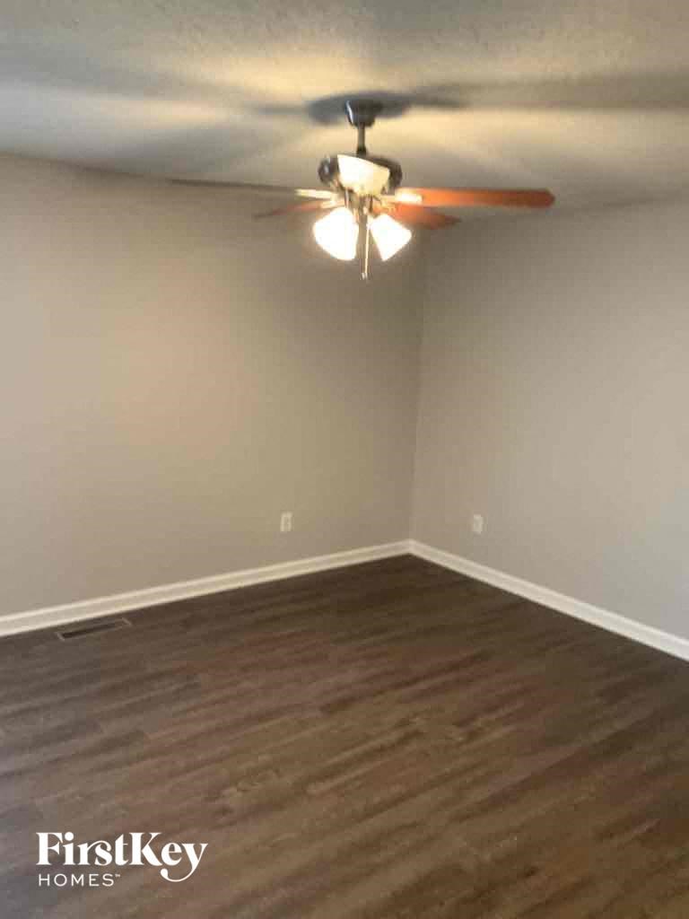 A room with a ceiling fan and wooden flooring.