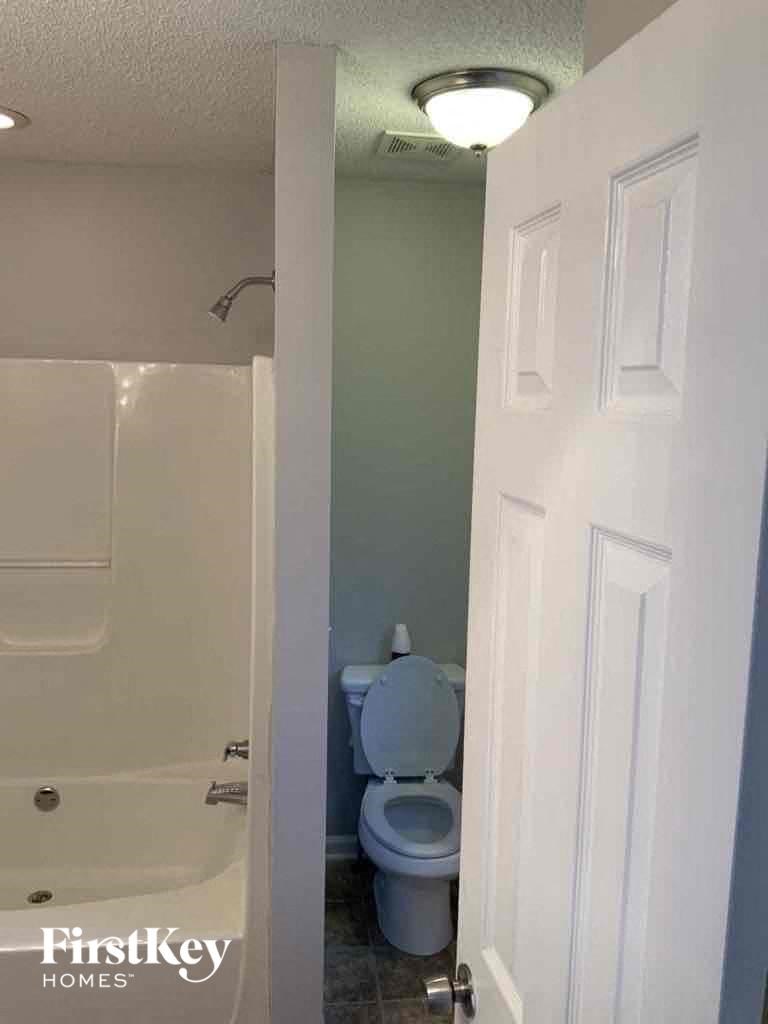 A white door is open to a bathroom with a toilet.