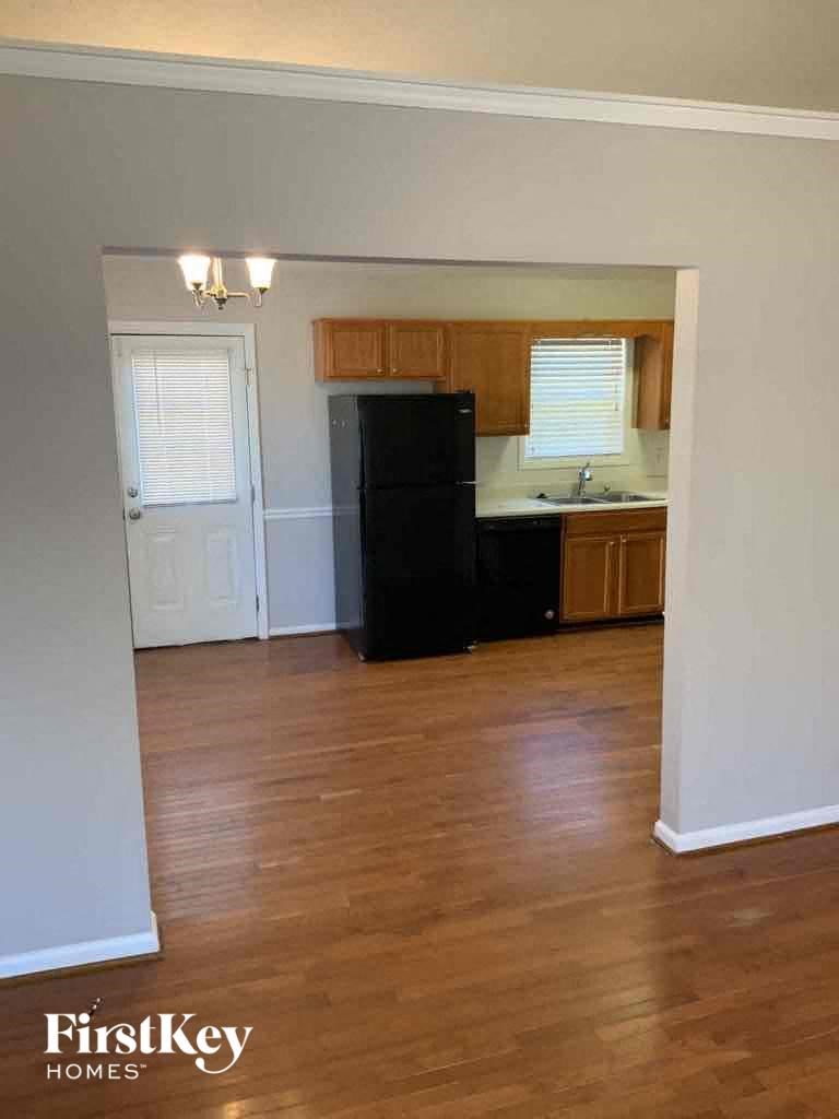A kitchen with wooden floors and a black refrigerator.