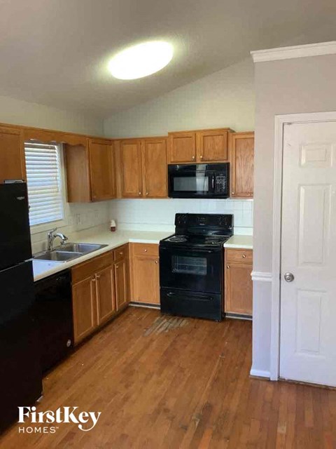 A kitchen with wooden cabinets and black appliances.