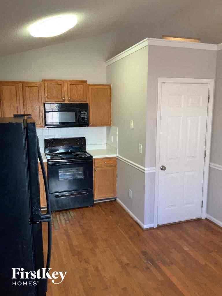 A kitchen with wood cabinets and a black fridge.