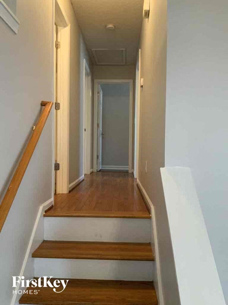 A hallway with a wooden staircase and white walls.