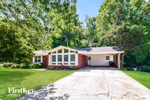 a white and brick house with a driveway and trees
