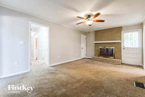 an empty living room with a ceiling fan and a fireplace