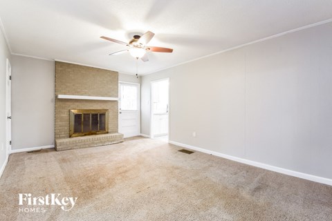 an empty living room with a fireplace and a ceiling fan