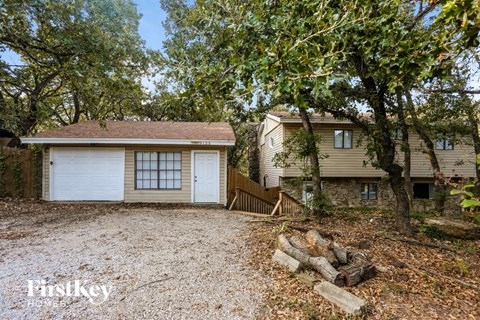 A house with a garage is surrounded by trees.