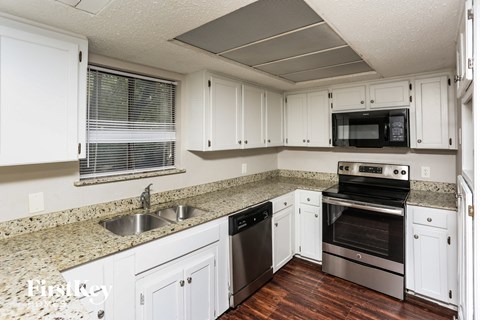 A kitchen with white cabinets and a granite countertop.