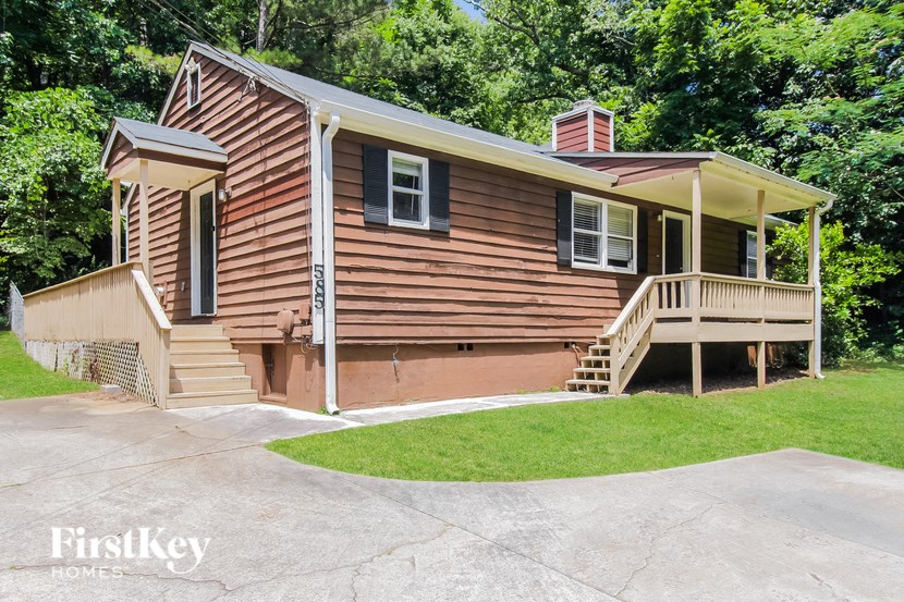 a small brown house with a porch and a driveway