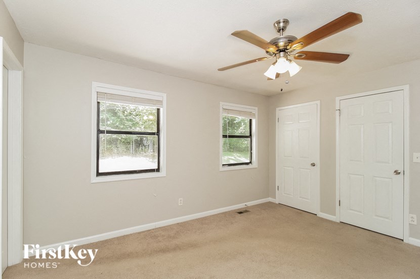an empty bedroom with a ceiling fan and two doors