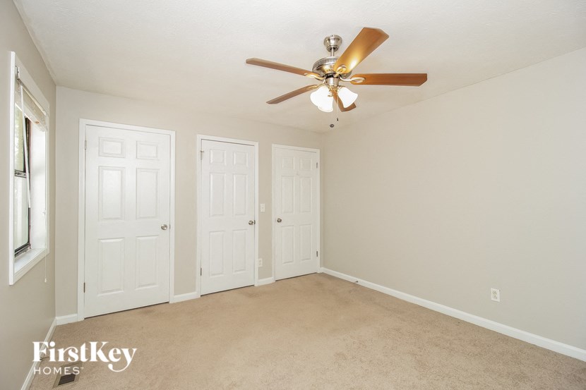 a bedroom with three doors and a ceiling fan