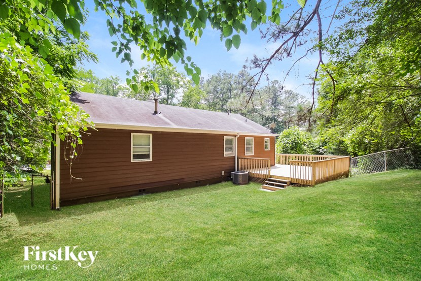 a backyard with a red house and a wooden deck