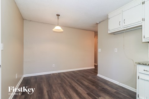 the living room of an apartment with white cabinets and wood flooring