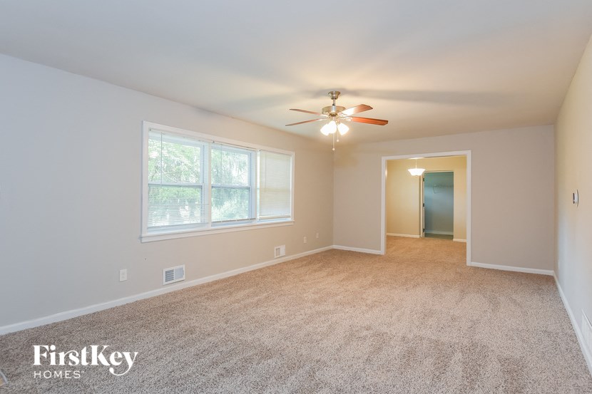 a empty living room with a ceiling fan and a window