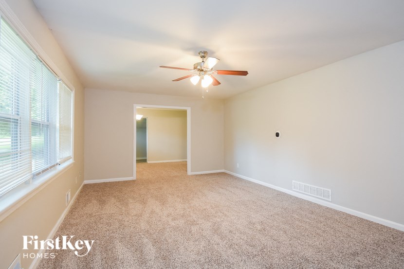 an empty living room with a ceiling fan and a large window