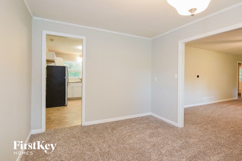 an empty living room with a doorway into a kitchen