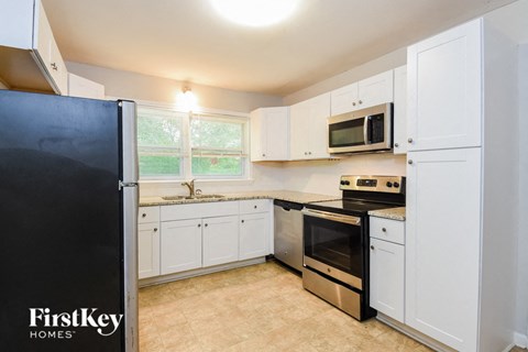 a kitchen with white cabinets and a black refrigerator