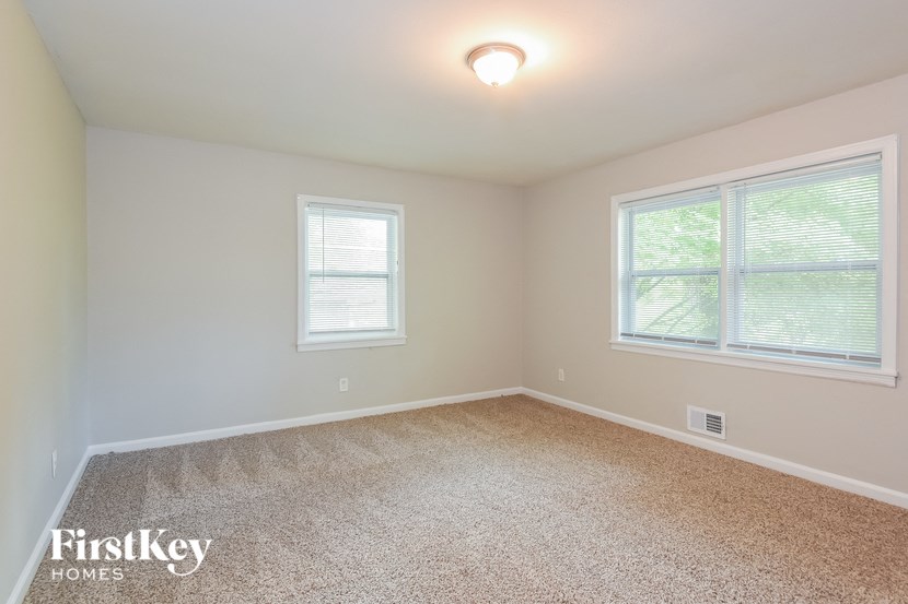 a bedroom with two windows and a carpeted floor