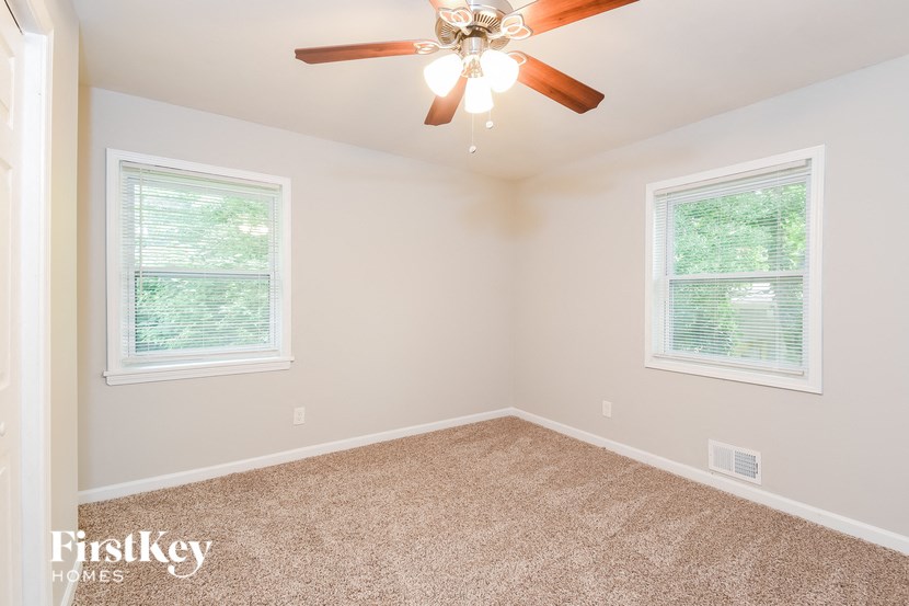 an empty bedroom with a ceiling fan and two windows