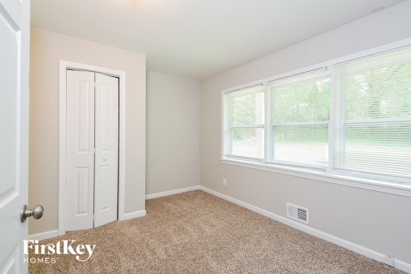 the bedroom of a home with a large window and a white door
