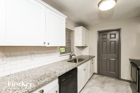 a kitchen with white cabinets and a counter top and a sink