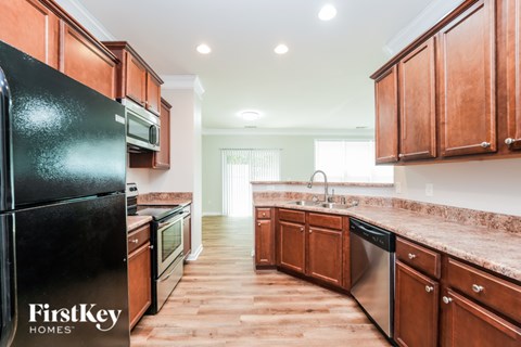 A kitchen with wooden cabinets and a black fridge.