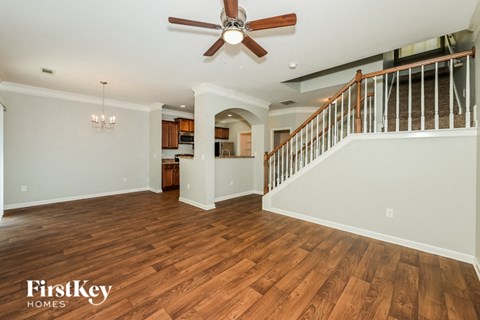 A spacious living room with wood flooring and a ceiling fan.