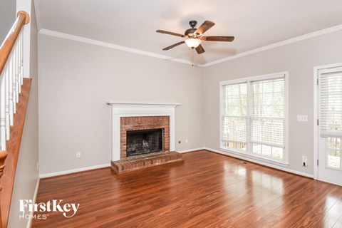 A living room with a fireplace and a ceiling fan.