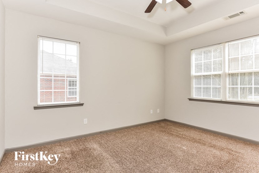 an empty room with two windows and a ceiling fan