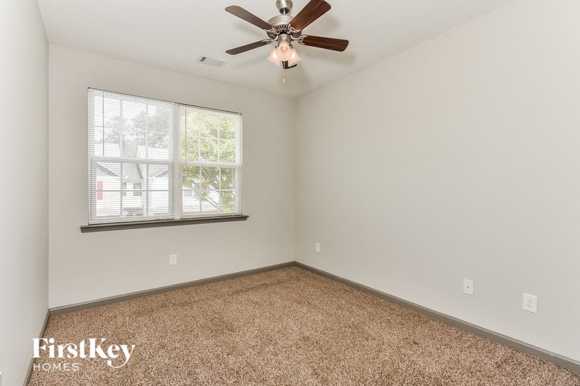 an empty bedroom with a ceiling fan and a window