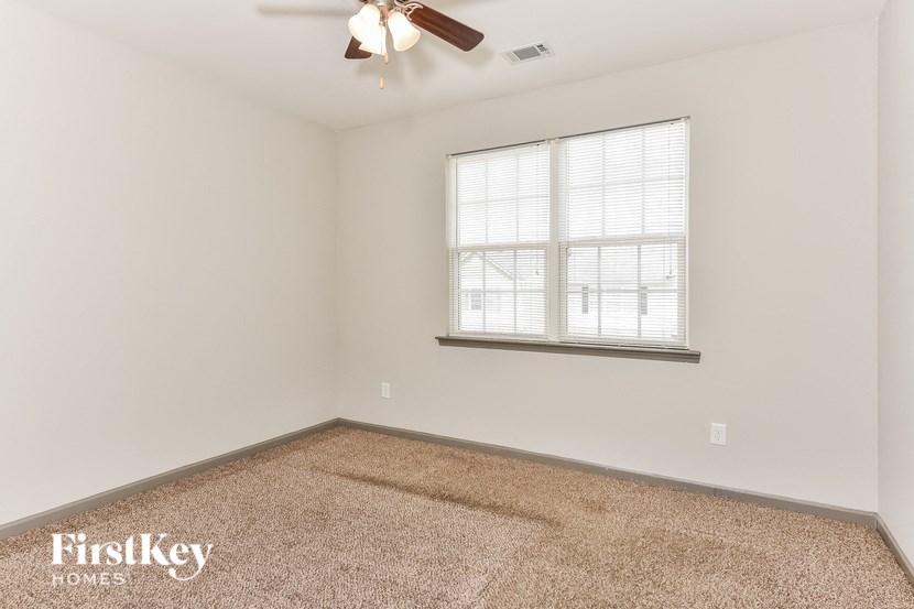 an empty room with a window and a ceiling fan