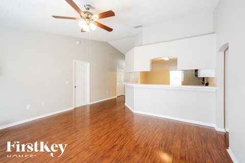 an empty living room with hardwood flooring and a ceiling fan