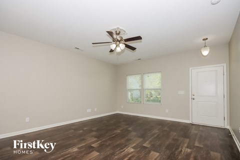 an empty living room with a ceiling fan and a white door