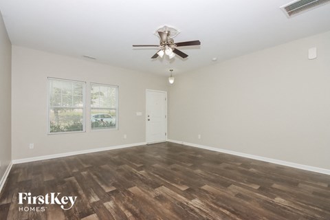 an empty living room with a ceiling fan and wood flooring