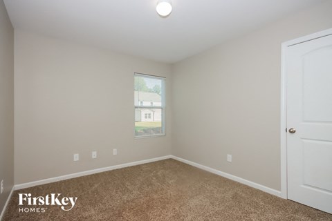 a bedroom with carpet and a window and a door