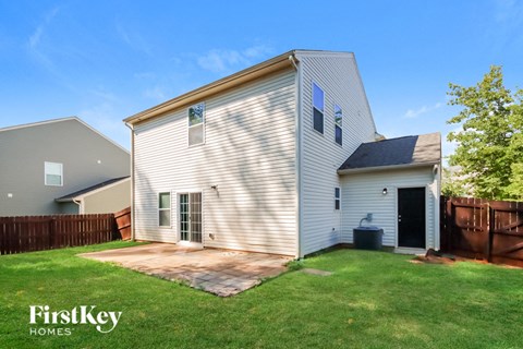 a backyard with a white house and a yard with grass