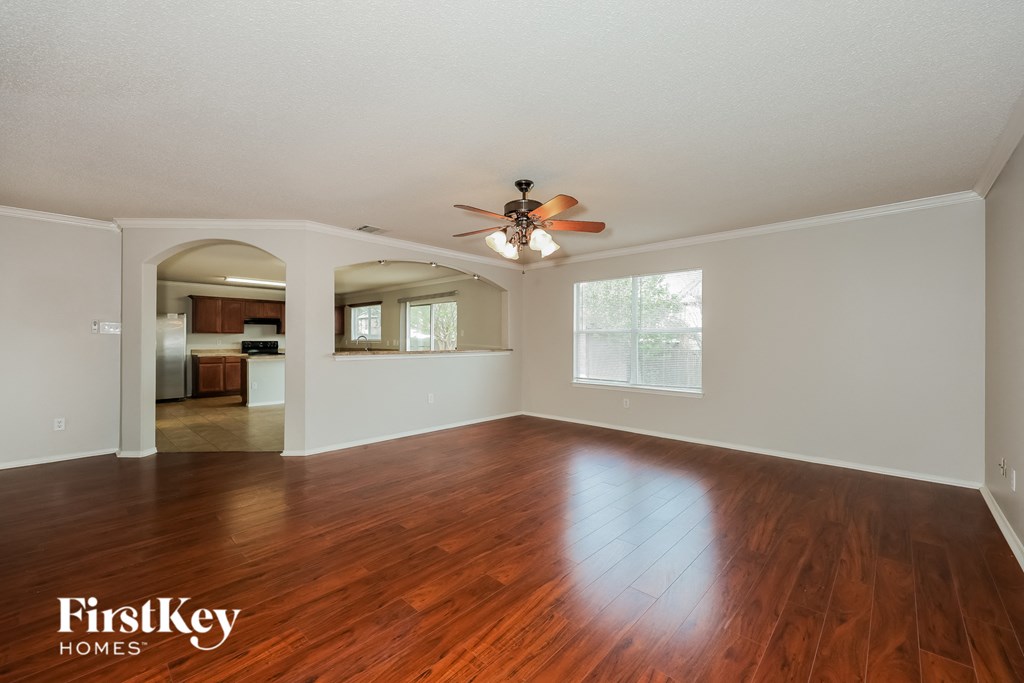 A spacious room with wooden floors and a ceiling fan.