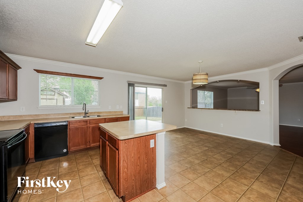 A kitchen with wooden cabinets and a black dishwasher.